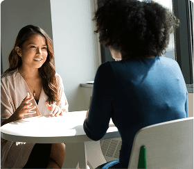 Two women talking while sitting at a table