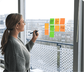 Woman writes on sticky notes attached to window